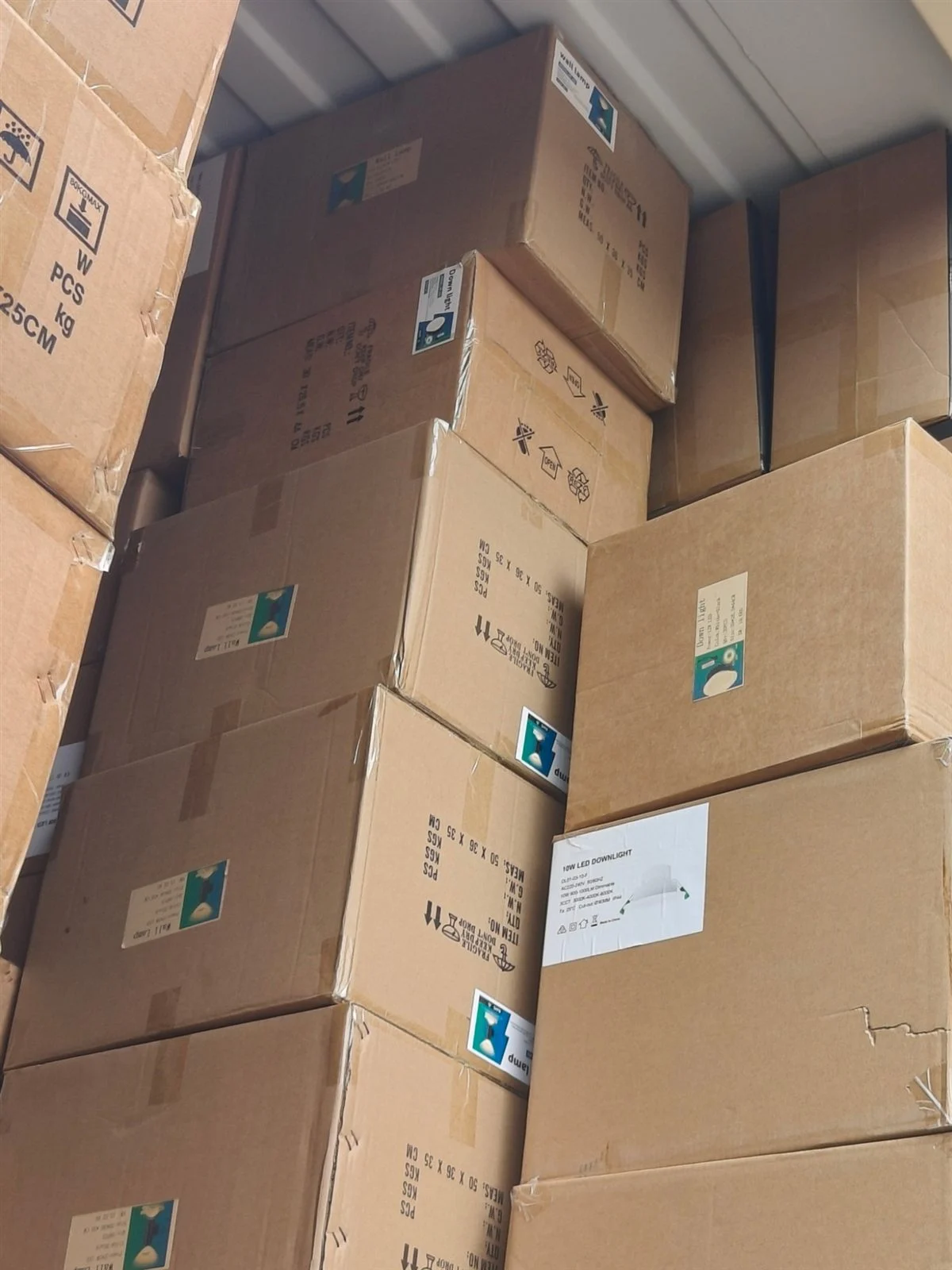 Mixed LED downlight and wall lamp cartons stacked inside a shipping container
